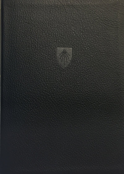 Funda de cuero negro para libros con un pequeño escudo en relieve que presenta un diseño estilizado de concha de vieira en el centro, perfecta para tu Biblia de estudio Reina-Valera 1995 o para tomar notas de estudio.