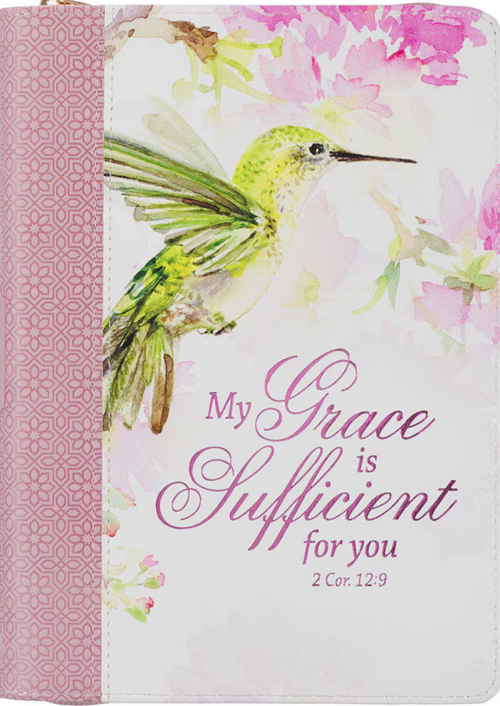 Una funda para cuaderno de imitación de piel rosa con un colibrí pintado en acuarela y flores rosas, en la que se lee «Mi gracia te basta, 2 Cor. 12:9» en letra cursiva rosa y morada. Incluye páginas rayadas con versículos bíblicos para inspirarte.