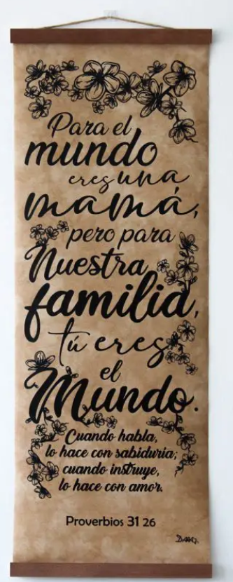 Decoración de pared con motivos florales y un mensaje inspirador en español para mamá, basado en Proverbios 31:26, que celebra el amor y la sabiduría familiar.