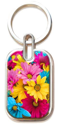 Un llavero metálico con un colgante rectangular que luce una colorida imagen de margaritas rosas, amarillas y azules, realzada con las inspiradoras palabras «Proverbios 3:3», como un suave recordatorio para llevar contigo el amor y la verdad allá donde vayas.