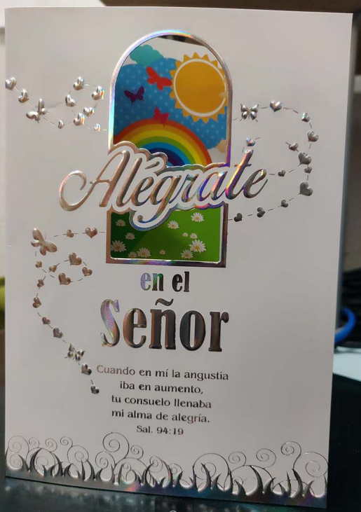 Tarjeta cristiana con texto plateado en relieve y una colorida ventana en la que se ven un sol, un arcoíris, mariposas y flores. El mensaje en español cita el Salmo 94:19 sobre encontrar alegría en el Señor; ideal como tarjeta de consuelo.