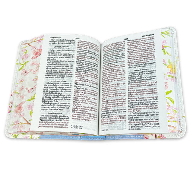 Se muestra una Biblia RVR60 abierta, con tapas decoradas con motivos florales, en la que se ven dos páginas repletas de texto en español y las «Palabras de Jesús» en rojo.