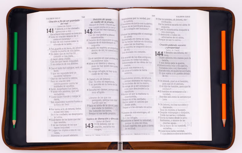 Una Biblia en español abierta, colocada en posición horizontal dentro de una funda de cuero sintético, con un lápiz verde a la izquierda y otro naranja a la derecha, abierta en Jeremías 29:11.