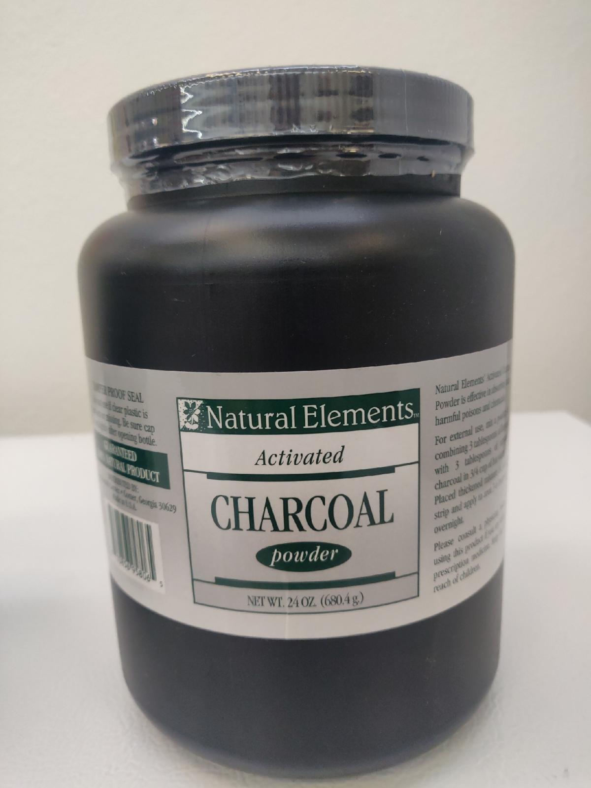 Un envase de plástico negro con la etiqueta «Natural Elements Activated Charcoal Powder» (carbón activado), con un peso neto de 24 oz (680,4 g), descansa sobre una superficie blanca con un fondo liso; ideal para ayudar con las molestias intestinales y los procesos de adsorción.
