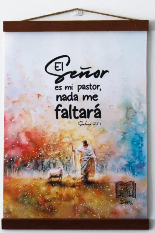 Un tapiz confeccionado en lienzo 100 % poliéster muestra una colorida ilustración de un pastor con un cordero y un texto en español: «El Señor es mi pastor, nada me faltará». Salmo 23:1.