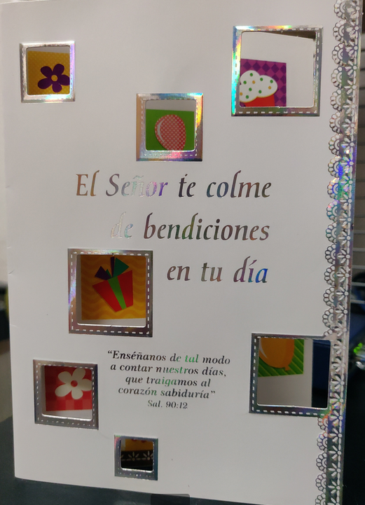 Tarjeta de cumpleaños decorativa con recortes cuadrados y un texto en español en el que se desean «bendiciones», con un versículo bíblico del Salmo 90:12 escrito en letras plateadas y de colores.