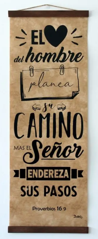 Un letrero colgante de madera con un texto en español de Proverbios 16:9, que dice que el hombre planea su camino, pero el Señor dirige sus pasos; una preciosa decoración cristiana para tu hogar.