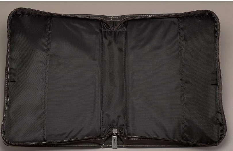 Una funda de cuero sintético negra, abierta y vacía, con cremallera y tres compartimentos principales, que se muestra colocada en posición horizontal sobre una superficie neutra; perfecta para llevar tu Biblia u otros objetos imprescindibles.