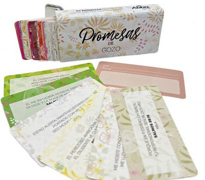 Una baraja de coloridas tarjetas con el título «Promesas de Gozo», en las que figuran diversas promesas bíblicas en español, dispuestas en abanico sobre una superficie blanca junto a una caja metálica.