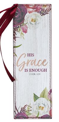 Un marcapáginas cristiano rectangular con motivos florales y una cinta granate lleva la inscripción «Su gracia me basta, 2 Cor. 12:9» sobre un fondo blanco con textura de madera.