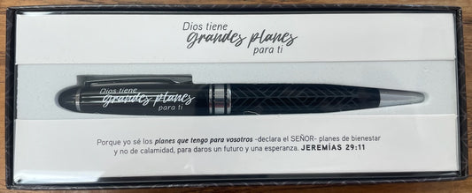 Una pluma en una elegante caja de regalo con la frase «Dios tiene grandes planes para ti» en español, acompañada de una tarjeta con el versículo bíblico de Jeremías 29:11 sobre los planes de Dios.