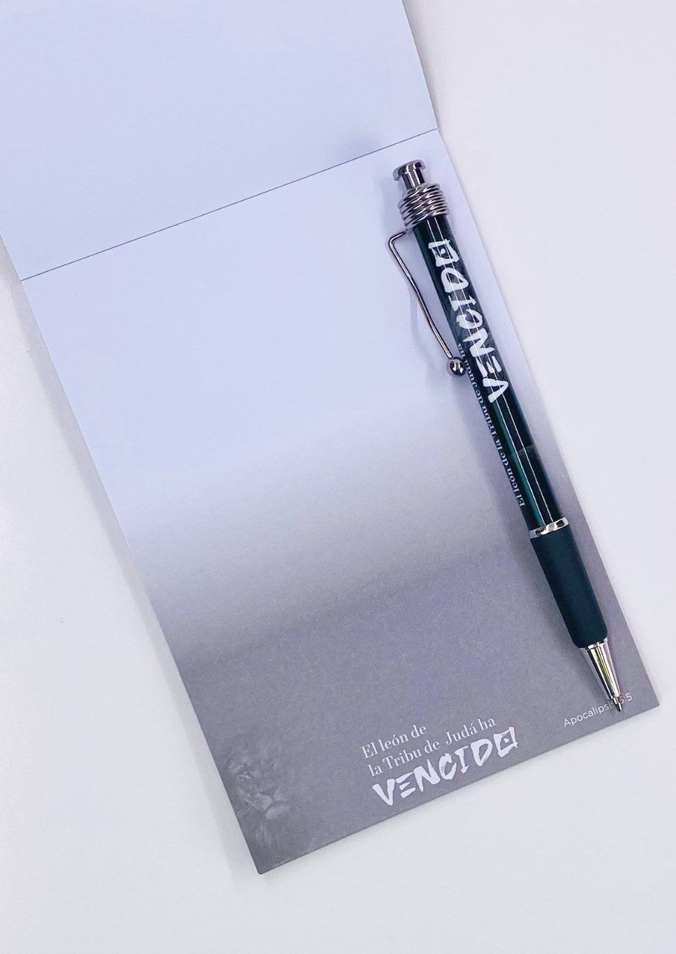 Un bloc de notas abierto con un bolígrafo incluido sujetado a la primera hoja. Tanto el bloc de notas como el bolígrafo muestran la palabra «VENCIDO», junto con otro texto más pequeño.