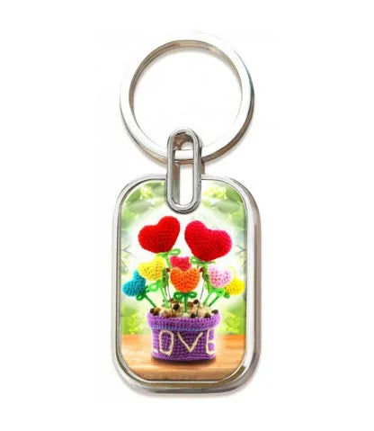 Llavero con una placa rectangular en la que aparece la foto de una maceta morada con la palabra «LOVE» escrita en ella, adornada con decoraciones de colores en forma de corazón: un bonito recordatorio para afrontar el miedo con confianza, inspirado en el Salmo 56:3.