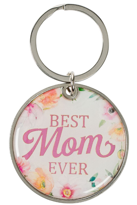 Un llavero redondo de metal en tono dorado con un borde floral y la frase «BEST MOM EVER» impresa en letras rosas sobre fondo blanco: un regalo ideal para el Día de la Madre.