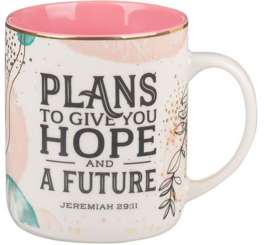Una taza de cerámica con el interior rosa y un diseño floral en el que se lee: «Planes para darte esperanza y un futuro. Jeremías 29:11». Capacidad: 14 fl oz; se recomienda lavarla a mano.