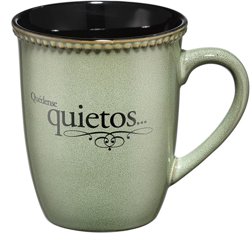 Una taza de cerámica verde de 14 oz con borde de cuentas, en la que figura el texto en español «Quédense quietos...» en letras negras, apta para el microondas.
