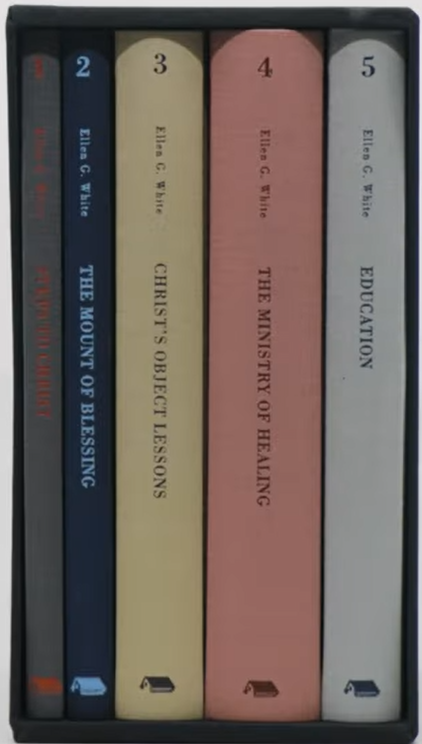 Cinco libros de Ellen G. White se presentan dispuestos verticalmente en una caja que contiene una colección de libros cristianos con letra grande; los títulos se ven en los lomos y cada libro tiene una cubierta de un color diferente.