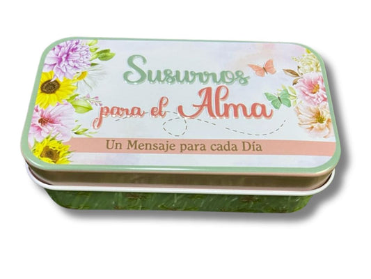 Una caja metálica rectangular con motivos florales y un texto en español que reza «Susurros para el alma, un mensaje para cada día» contiene tarjetas cristianas con versículos bíblicos inspiradores para cada ocasión.