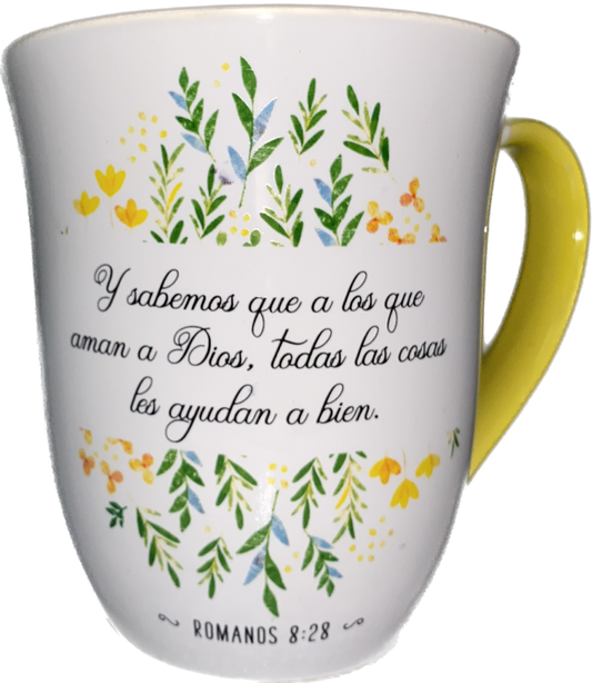 Taza blanca con asa amarilla, decorada con motivos florales, en la que figura un versículo de la Biblia en español, de Romanos 8:28, sobre cómo Dios hace que todo contribuya al bien.