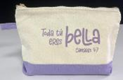 Una bolsa de algodón con cremallera, de color beige y morado, con el texto en español «Toda tú eres bella» y «Cantares 4:7» impresos en la parte delantera.