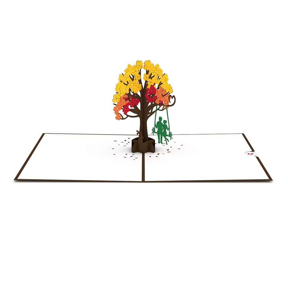 Una impresionante tarjeta de felicitación de 5 x 7; esta tarjeta de alta calidad muestra un árbol en 3D con hojas amarillas y naranjas y dos figuras verdes en un columpio que cuelga de una rama.