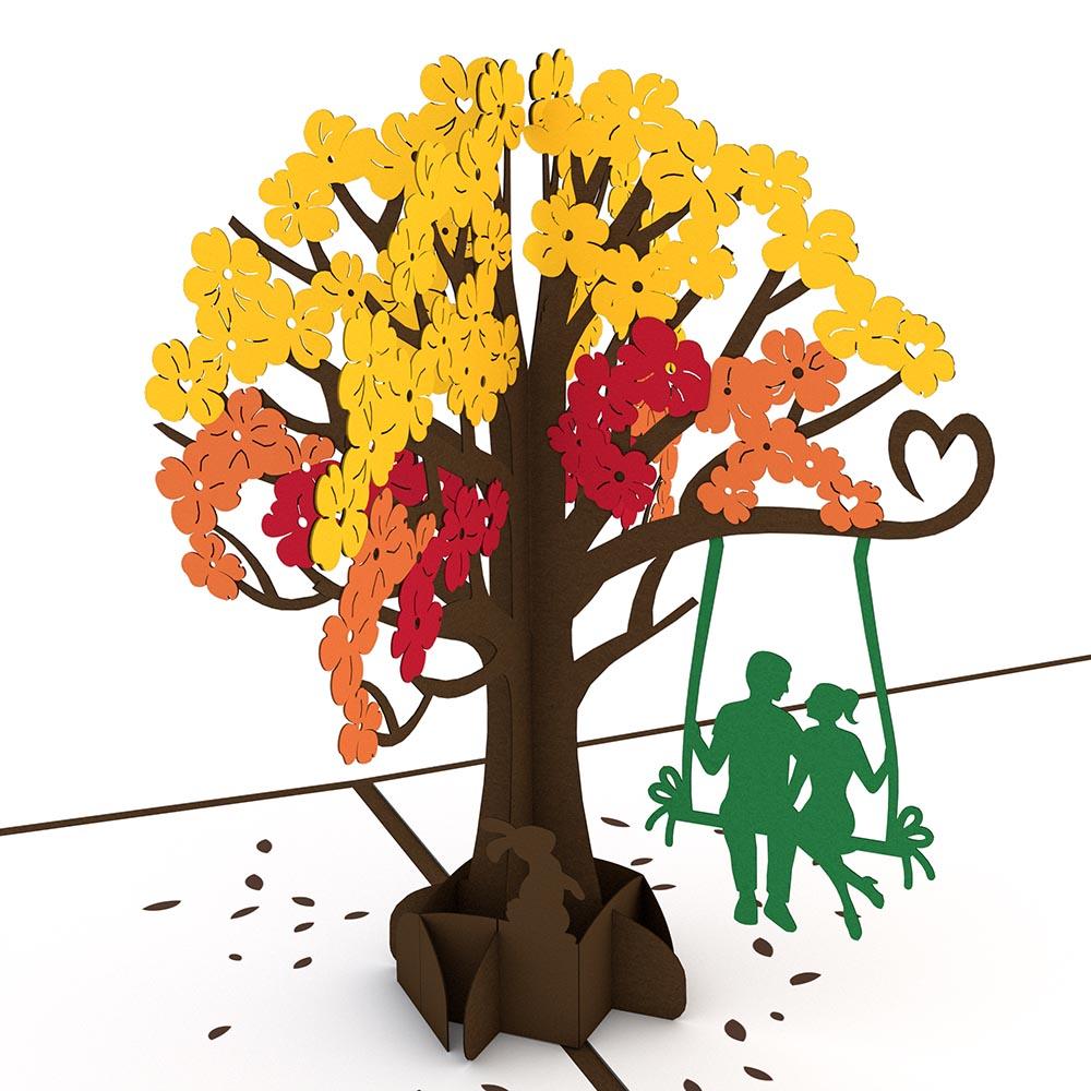 Un árbol de papel con hojas amarillas y naranjas, una forma de corazón entre las ramas y dos personas en un columpio colgado de una rama: perfecto como tarjeta de alta calidad o tarjeta de 5 x 7 para cualquier ocasión especial.