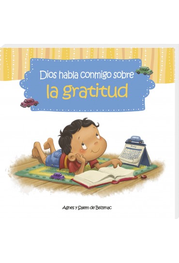 Un niño está tumbado sobre una alfombra, leyendo un libro, con un calendario, un lápiz de colores y unos cochecitos a su lado. En la portada del libro se lee: «Dios habla conmigo sobre la gratitud».