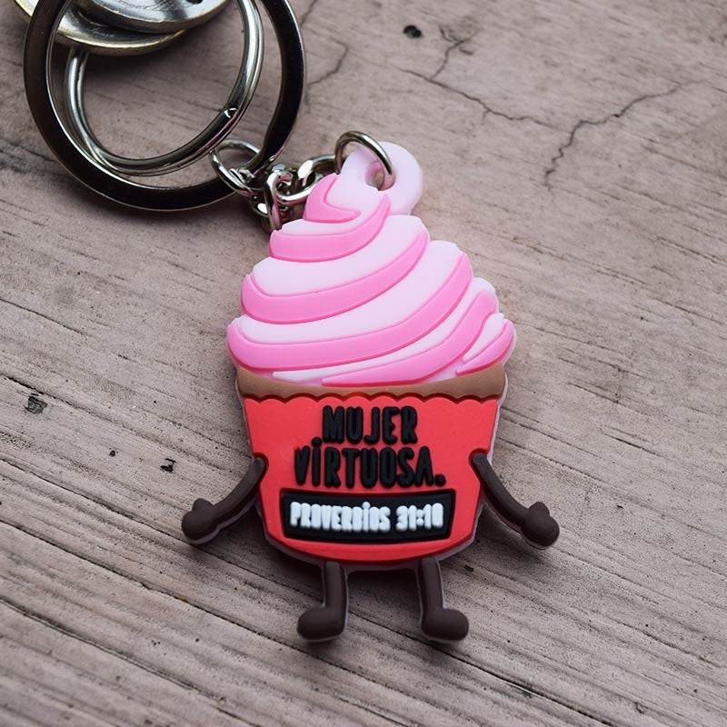 Un divertido llavero con forma de cupcake, con brazos y piernas, decorado con glaseado rosa y la frase «Mujer virtuosa. Proverbios 31:10», que aparece en la parte delantera, ideal para inspirarte cada día.