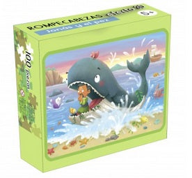 Un rompecabezas de 100 piezas para niños en una caja de metal, en el que aparece una ballena de dibujos animados con un niño y otros animales en la boca, chapoteando en el océano junto a un barco y una isla; perfecto para niños de 5 años.