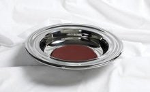 Una bandeja redonda de plata con la base de fieltro rojo descansa sobre una superficie de tela blanca, ideal para su próxima compra de productos o para quienes deseen realizar la compra directamente; llámenos para obtener más información.