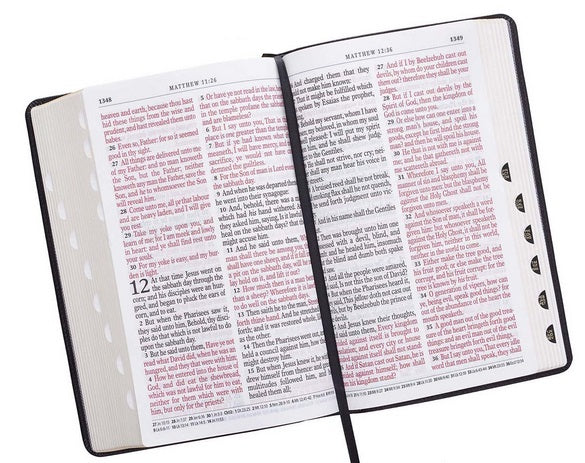Una Biblia de letra grande abierta, con páginas con bordes dorados, texto en tinta negra y roja, un marcapáginas de cinta negra y separadores de páginas visibles a la derecha.