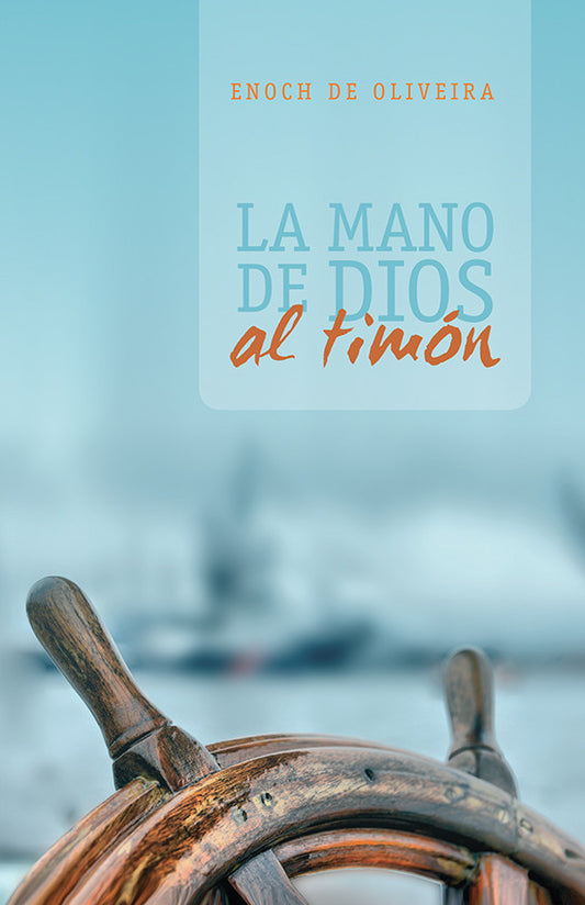 Portada del libro en la que aparece enfocado el timón de madera de un barco, con un paisaje marino difuminado al fondo. El título reza «La Mano de Dios al Timón», de Enoch de Oliveira, y destaca el triunfo religioso a través de la dirección divina.
