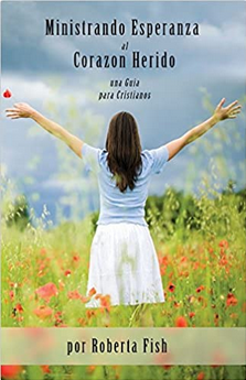 Una mujer aparece de pie en un campo con los brazos extendidos; en la portada del libro se lee «Ministrando Esperanza al Corazón Herido», de Roberta Fish, que ofrece orientación y esperanza a los supervivientes de abusos y a quienes se han visto afectados por los abusos en la Iglesia.