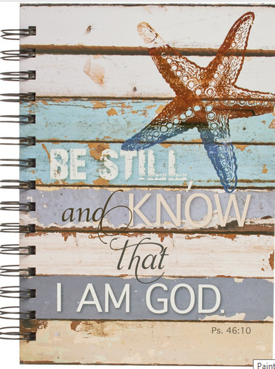 Un cuaderno con espiral en el que aparece una estrella de mar y el texto: «Quédate quieto y reconoce que yo soy Dios. Sal. 46:10», sobre un fondo de madera desgastada, con páginas rayadas para que anotes tus pensamientos.