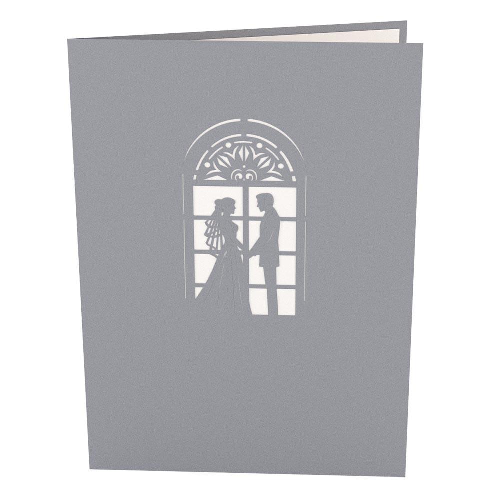 Una tarjeta gris de 5 x 7 con un diseño recortado en el que se ve a una novia y un novio de pie juntos delante de una ventana en arco.