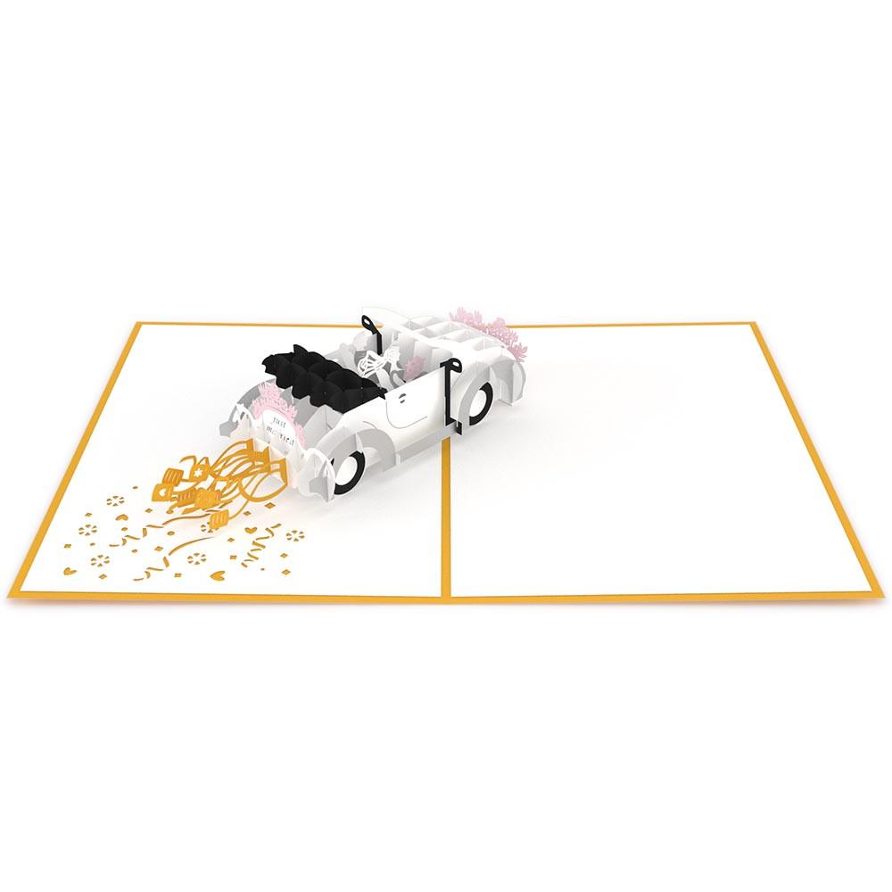 Una tarjeta de alta calidad de 5 x 7 tipo pop-up, con un descapotable blanco decorado con el mensaje «Just Married», flores rosas y confeti dorado sobre fondo blanco y borde naranja.