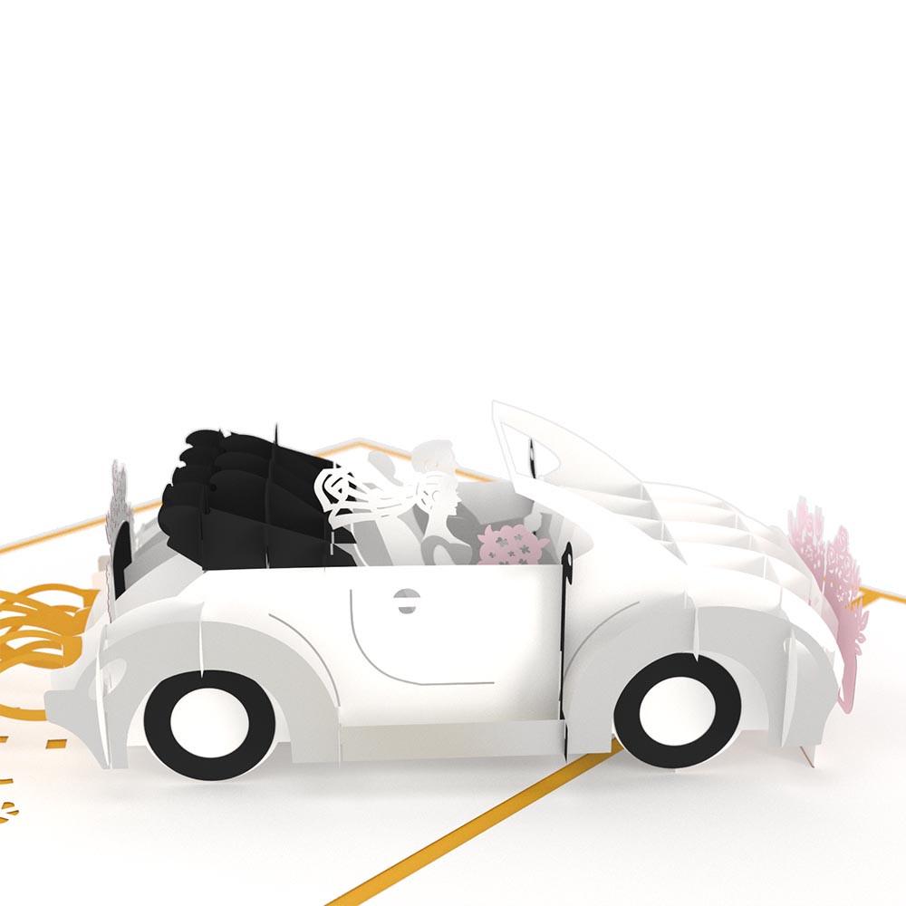 Tarjeta de 5 x 7 de alta calidad con un diseño pop-up: un descapotable blanco con los recién casados sentados, decorado con flores rosas.