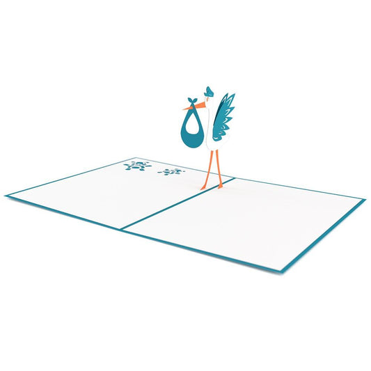 Una tarjeta de felicitación pop-up de alta calidad en la que aparece una cigüeña azul y blanca sosteniendo un pañalito, abierta sobre una superficie blanca, con bordes azules y un pequeño diseño azul en el interior. Esta tarjeta de 5 x 7 es perfecta para ocasiones especiales.