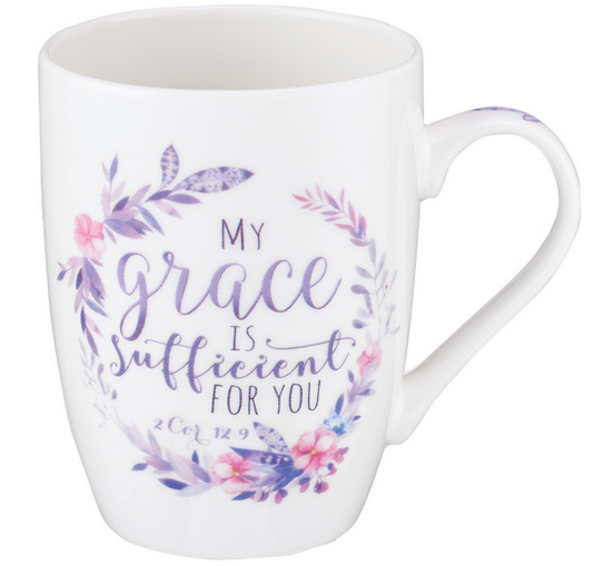 Una taza de cerámica blanca apta para microondas, decorada en la parte delantera con una corona floral morada y el texto «Mi gracia te basta, 2 Cor 12,9», ideal como regalo especial y disponible con una caja de regalo opcional.
